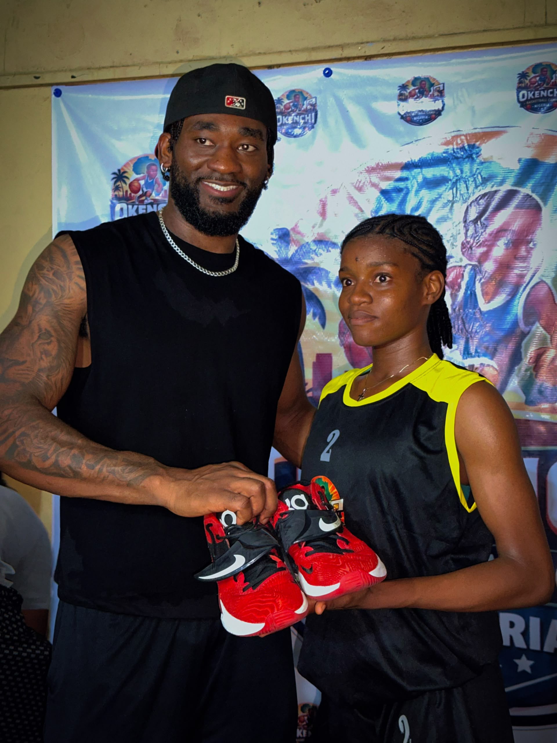 Eric Okenchi presenting donated basketball shoes to a young athlete