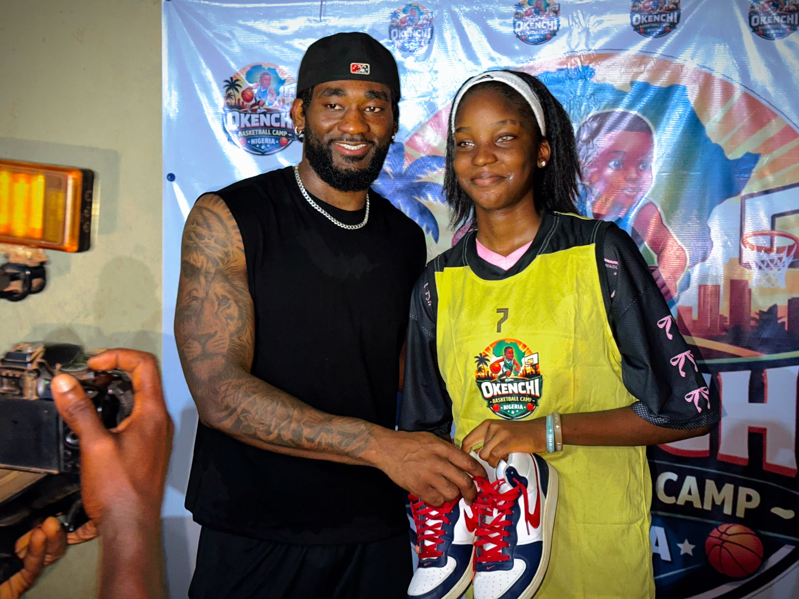 Eric Okenchi presenting new basketball shoes to a camper in a yellow jersey